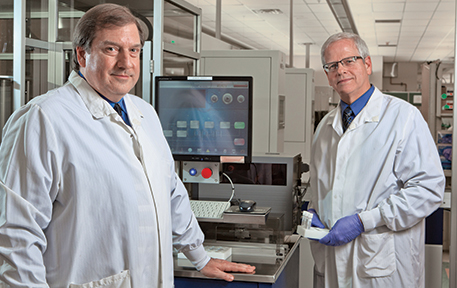 Kahn, left, and Clark at Alverno central laboratory, where the benefits of automation in terms of staff time have been seen already. Left: Canister from the unload stacker station of Copan WASPLab with plates that have been designated by digital image review to be removed from the incubator for transfer to a workstation to complete ID and susceptibility testing processing.