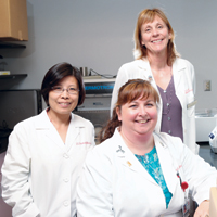 Dr. Vance (standing), director of the IU Division of Diagnostic Genomics, with Shaochun Bai, PhD (left), director of the molecular diagnostic laboratory, and Lisa Lowe Wright, lab manager of the cytogenetics labs, which submit samples to ECOG for review.